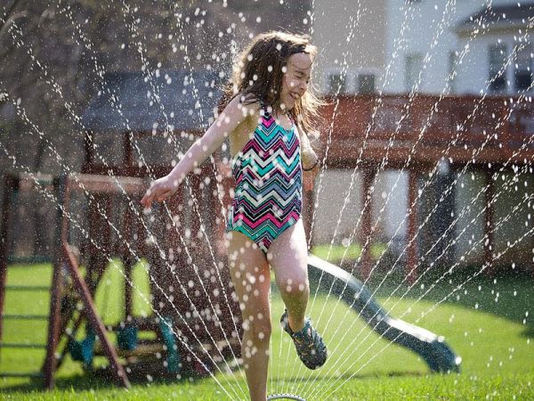 Girl running through a sprinkler. Photo credit: Austin Kirk